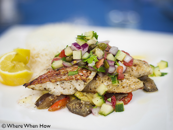 A photograph of Fresh locally caught Snapper filet with salsa and sauteed vegetables at Ocean Club Plaza, Providenciales (Provo), Turks and Caicos Islands.